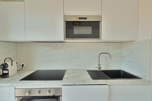 une cuisine blanche avec un évier et un micro-ondes dans l'établissement Mireille, à Cannes