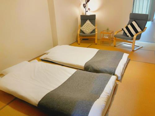 a bedroom with a large bed and a chair at SLOW HOUSE NARA in Nara