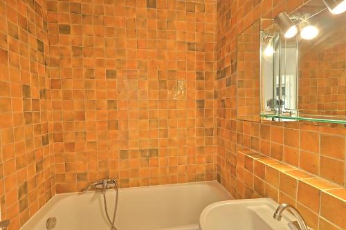 La salle de bains est pourvue de carrelage orange, d'une baignoire et de toilettes. dans l'établissement Mireille, à Cannes