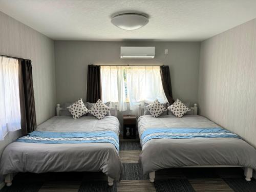 two beds in a room with two windows at サンライズハウス in Osaka
