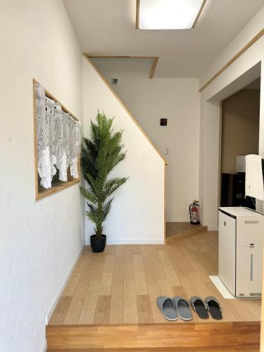 a living room with a plant and a staircase at サンライズハウス in Osaka