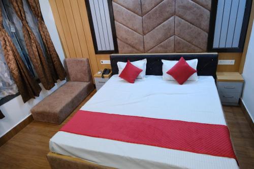 a bedroom with a bed with red and white pillows at Hotel Golden Continental in Deoghar