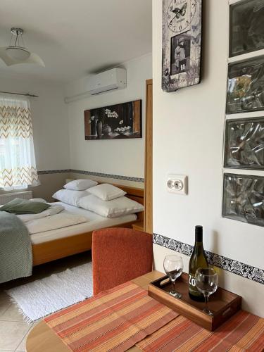 a bedroom with a bed and a table with a bottle of wine at Réka Apartmanház in Bük