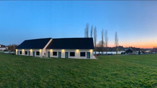 une maison blanche avec un toit noir dans un champ dans l'établissement Résidence du lac, à Bourbon-Lancy