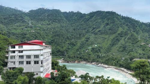 a building with a red roof next to a river at SPT Clarks Inn Suite, Mandi in Pāndoh