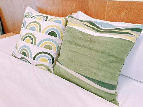 two green and white pillows on a bed at Gardenstay in Luodong