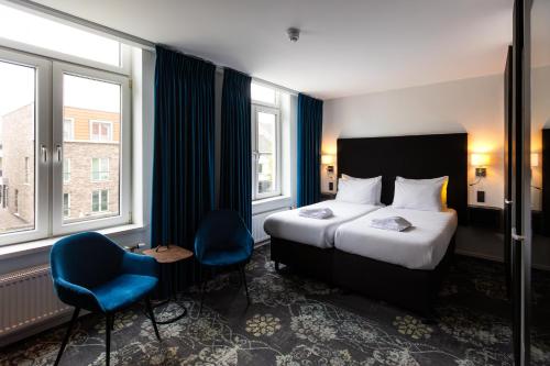 een hotelkamer met een bed en een blauwe stoel bij Atlas Hotel in Valkenburg