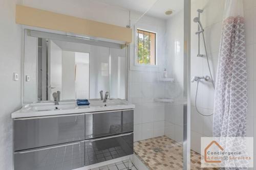 un bagno bianco con lavandino e doccia di Maison Évasion - Piscine, Jardin & Barbecue a Oullins