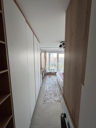 a hallway with a bed and a room with a window at Skyline Prishtina Studio Apartment in Pristina