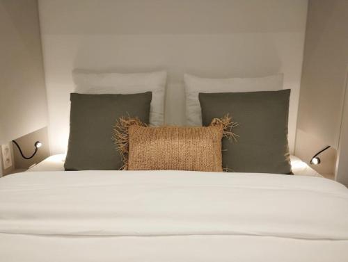 - un lit avec quatre oreillers et un couvre-lit blanc dans l'établissement Appartement centre ville idéal cures proche gare, à Aix-les-Bains