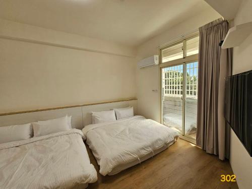 two beds in a room with a large window at Dessert No8 Homestay in Beinan
