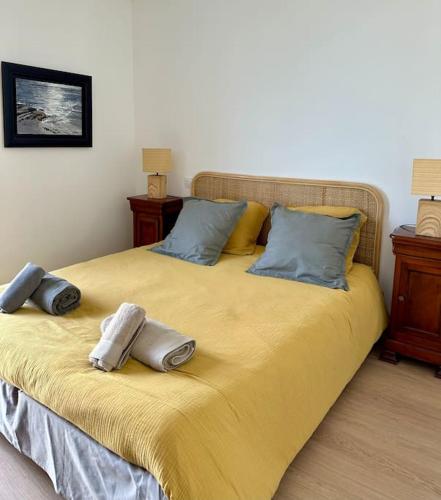 - un grand lit jaune avec deux oreillers dans l'établissement Appartement vue mer, plage et centre ville à pied, à Concarneau