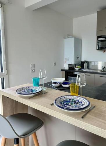 - une cuisine avec des assiettes et des verres à vin sur un comptoir dans l'établissement Appartement vue mer, plage et centre ville à pied, à Concarneau