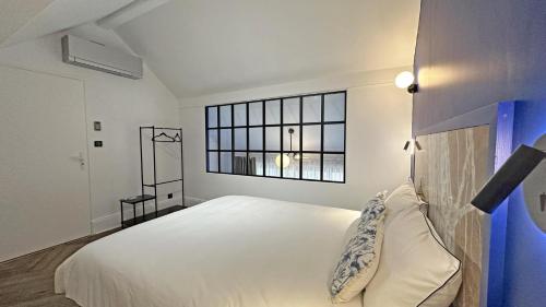 a white bedroom with a large bed and a window at Gite du manoir des perrieres in Rochechouart