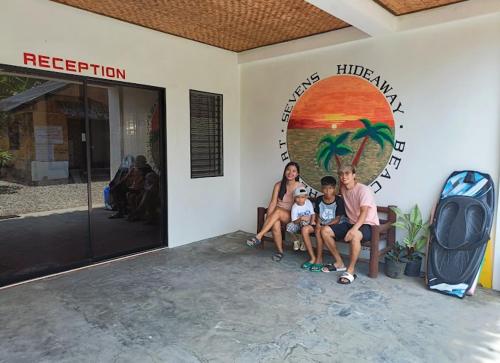a family sitting on a bench outside of a hotel at Sevens Hideaway Beach Resort in Siaton