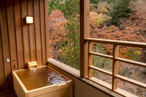 a bath tub in a room with a large window at Shionoyu Onsen Rengetsu in Nasushiobara