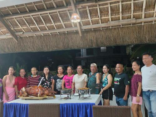 a group of people standing around a table with a turkey at Sevens Hideaway Beach Resort in Siaton