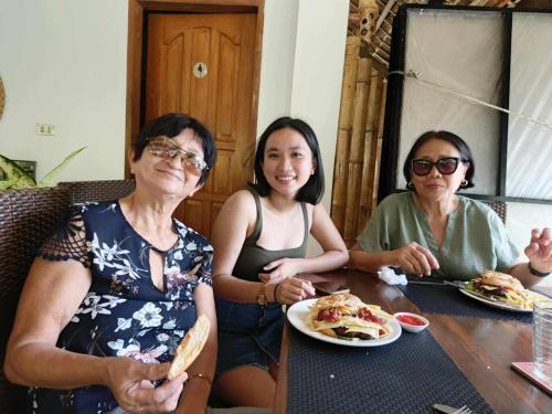 three women sitting at a table with a plate of food at Sevens Hideaway Beach Resort in Siaton
