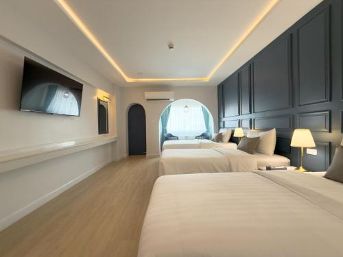 a hotel room with three beds and a flat screen tv at Regent Ramkhamhaeng 22 in Bangkok
