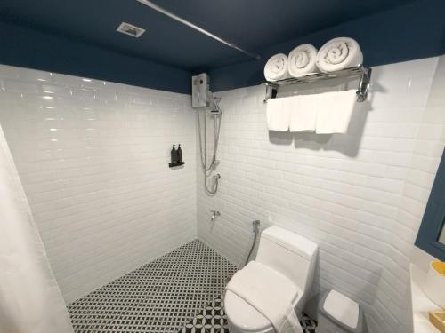 a white bathroom with a toilet and towels at Regent Ramkhamhaeng 22 in Bangkok