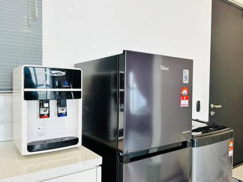 a stainless steel refrigerator next to a stove in a kitchen at Urban Suites Cozy Home with Netflix and Board games in Jelutong