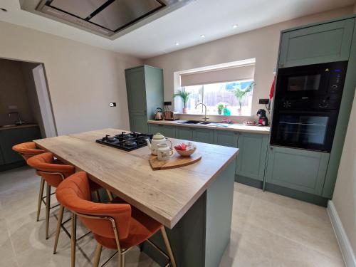 a kitchen with a large wooden table with orange chairs at Stylish and Modern 7 Bedroom house near Brecon Beacons in Cefn-coed-y-cymmer