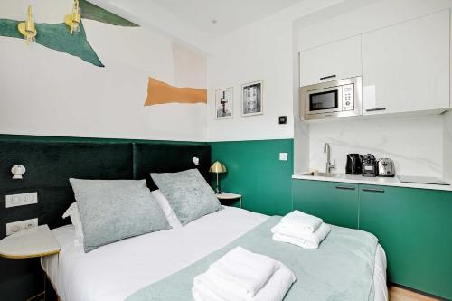 une chambre verte et blanche avec un lit et un micro-ondes dans l'établissement Modern Studio with A-C - Near Montmartre, à Paris