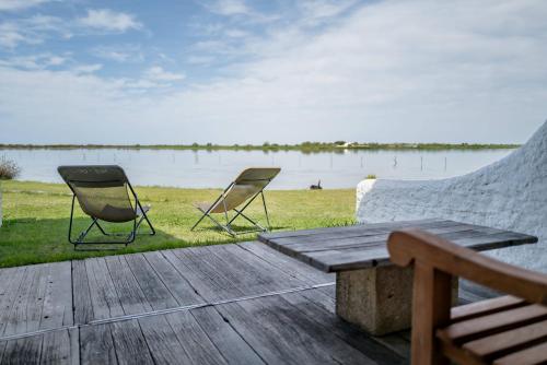 two chairs and a table on a deck near a lake at Lodge Sainte Helene Adult only in Saintes-Maries-de-la-Mer