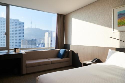 a hotel room with a bed and a couch and a window at Nine Tree by Parnas Seoul Myeongdong 2 in Seoul