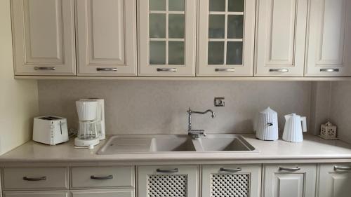a kitchen counter with a sink and white cabinets at Oikia Apozari Megalos Filippos in Kastoria