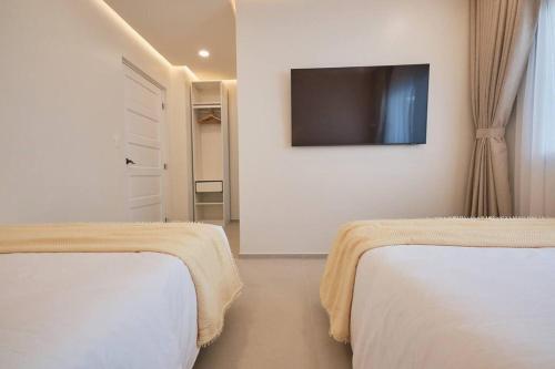 two beds in a room with a tv on the wall at Alesea Tammocalao La Union Beachfront Villa - Jacuzzi, Two Pools in Bacnotan