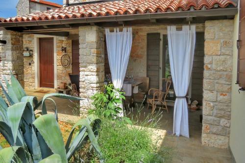 a stone house with white curtains on a patio at Casa Le Finide in Bale
