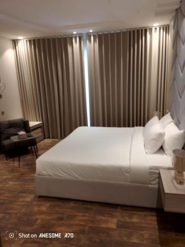 a bedroom with a large white bed and a chair at Dorm Story For Hotel Apartment in Taif