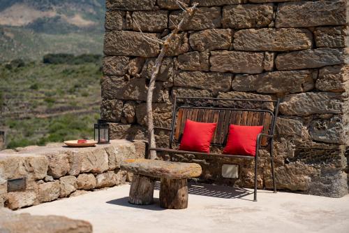 a bench with red pillows sitting in front of a stone wall at Kuddia Attalora in Pantelleria