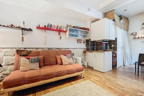 - un canapé brun dans le salon avec cuisine dans l'établissement Charming Studio Near Le Louvre Rivoli, à Paris