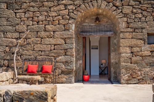 a stone wall with two red pillows on a bench at Kuddia Attalora in Pantelleria