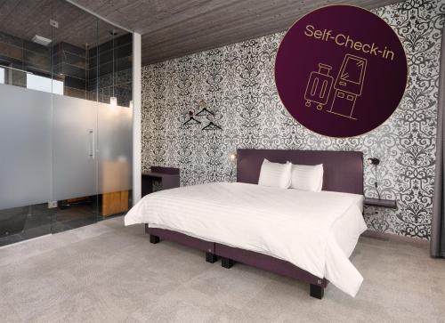 a bedroom with a bed and a purple sign on the wall at b-smart hotel Menziken in Menziken