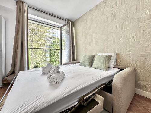 un grand lit dans une chambre avec une fenêtre dans l'établissement Appartement Cosy 2P- Trocadero La Muette, à Paris
