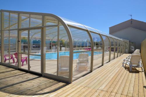 une terrasse avec une piscine et un bâtiment en verre dans l'établissement Mobil-home 1 chambre 2 personnes à 15 min des Sables d'Olonne, à Vairé