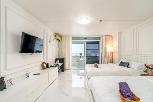 a hotel room with two beds and a flat screen tv at Bang Saen Royal Beach by Sea view Bang Saen in Ban Laem Thaen