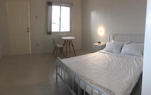 ein Schlafzimmer mit einem Bett und einem Tisch und einem Fenster in der Unterkunft Westward Surf Zambales Beach Resort in La Paz