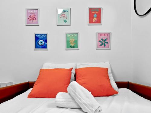 un lit avec deux oreillers orange et des tableaux sur le mur dans l'établissement Charmant studio 2P - 5' Tour Eiffel, à Paris