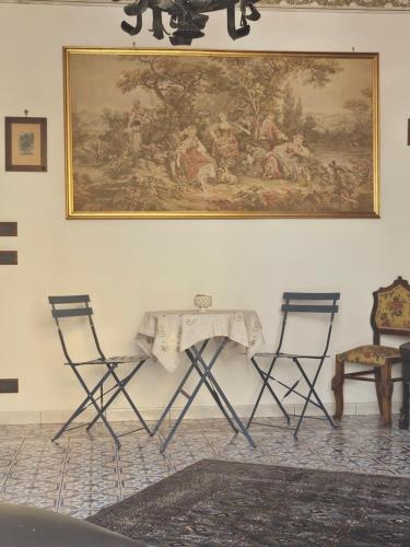 a table with two chairs and a painting on the wall at casa Ennio by Villa Paola Ciminna in Ciminna