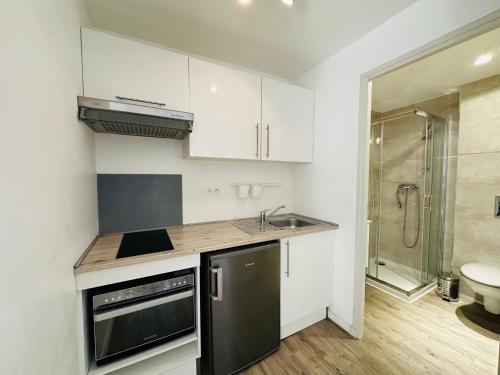 La cuisine est équipée de placards blancs, d'un lavabo et d'une douche. dans l'établissement Résidence 41 Léon Noel, à Cannes