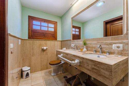 łazienka z umywalką, toaletą i lustrem w obiekcie Villas la Gomera w mieście Alajeró