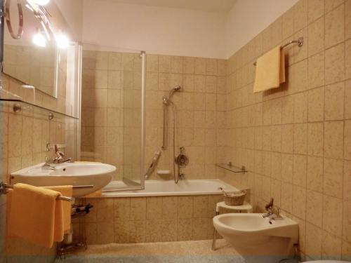 a bathroom with a sink and a tub and a toilet at Appartments Innerhofer in Rifiano