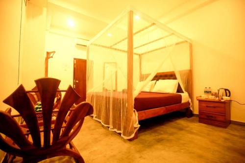 a bedroom with a canopy bed and a chair at Surf Heavens in Dickwella