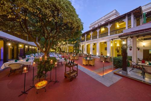 an outdoor patio with tables and chairs and a tree at Royal Orchid Metropole Mysore in Mysore