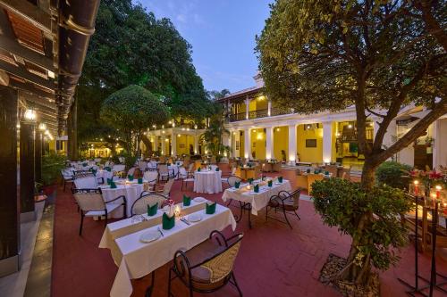 a restaurant with white tables and chairs and trees at Royal Orchid Metropole Mysore in Mysore