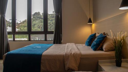 a bedroom with a bed with blue pillows and a window at Hotel Brynton at Cameron Centrum Mall in Cameron Highlands